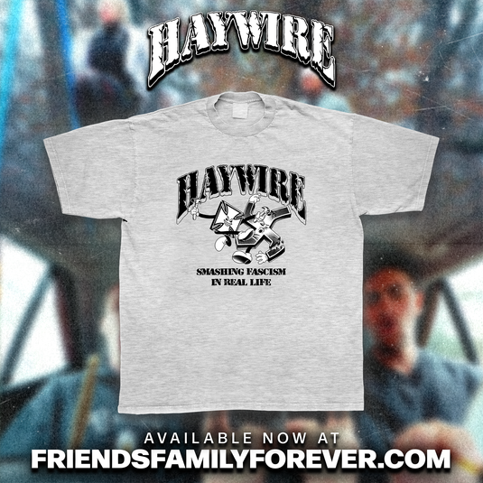 A light heather ash gray t-shirt with a black graphic print featuring 'HAYWIRE' logo and 'smashing fascism in real life' design graphic print